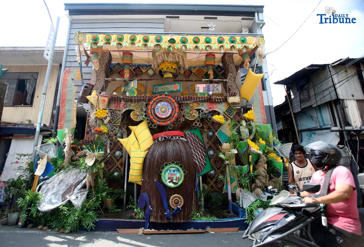 (December 01 2025) Pedestrians walk past houses decorated with colourful reusable materials as part of the 2025 SumBingTik (Suman, Bibingka, Latik) Festival in Cainta, Rizal on Monday December 1 2025. The SumBingTik Festival is an annual cultural long-week festival held in Cainta, Rizal, along with the town's founding anniversary and the feast of Our Lady of Light which is celebrated on December 1, the patron saint of the town. The festival was first celebrated in 2014. Photo/Analy Labor