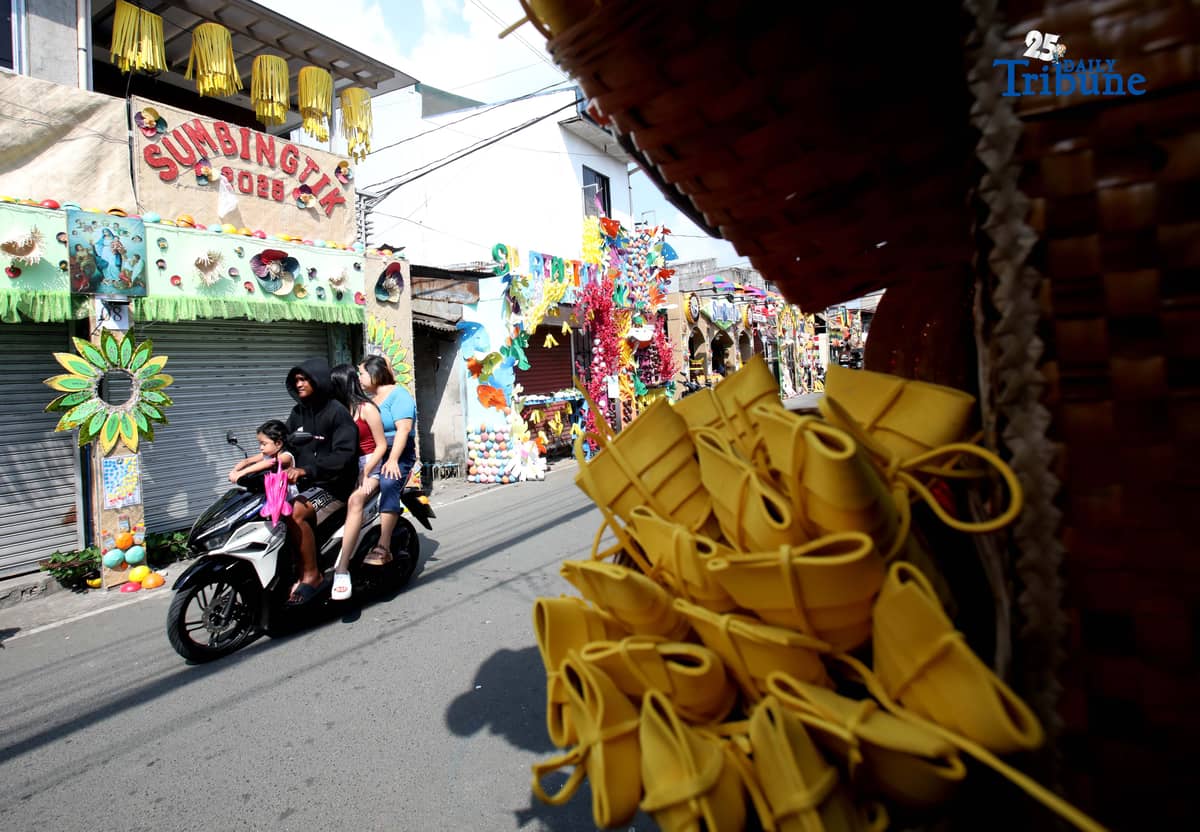 (December 01 2025) Pedestrians walk past houses decorated with colourful reusable materials as part of the 2025 SumBingTik (Suman, Bibingka, Latik) Festival in Cainta, Rizal on Monday December 1 2025. The SumBingTik Festival is an annual cultural long-week festival held in Cainta, Rizal, along with the town's founding anniversary and the feast of Our Lady of Light which is celebrated on December 1, the patron saint of the town. The festival was first celebrated in 2014. Photo/Analy Labor