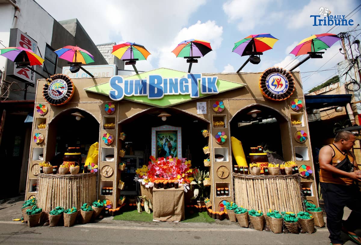 (December 01 2025) Pedestrians walk past houses decorated with colourful reusable materials as part of the 2025 SumBingTik (Suman, Bibingka, Latik) Festival in Cainta, Rizal on Monday December 1 2025. The SumBingTik Festival is an annual cultural long-week festival held in Cainta, Rizal, along with the town's founding anniversary and the feast of Our Lady of Light which is celebrated on December 1, the patron saint of the town. The festival was first celebrated in 2014. Photo/Analy Labor