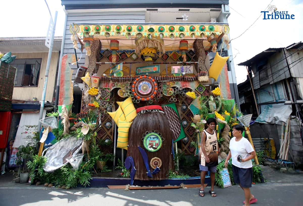(December 01 2025) Pedestrians walk past houses decorated with colourful reusable materials as part of the 2025 SumBingTik (Suman, Bibingka, Latik) Festival in Cainta, Rizal on Monday December 1 2025. The SumBingTik Festival is an annual cultural long-week festival held in Cainta, Rizal, along with the town's founding anniversary and the feast of Our Lady of Light which is celebrated on December 1, the patron saint of the town. The festival was first celebrated in 2014. Photo/Analy Labor