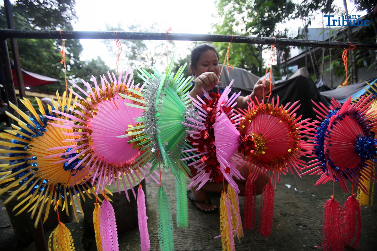 With 22 days before Christmas, a woman inspects a handmade lantern crafted from disposable straws in their compound on Wednesday, December 3. She said they created the décor to help bring the Christmas spirit to the community.