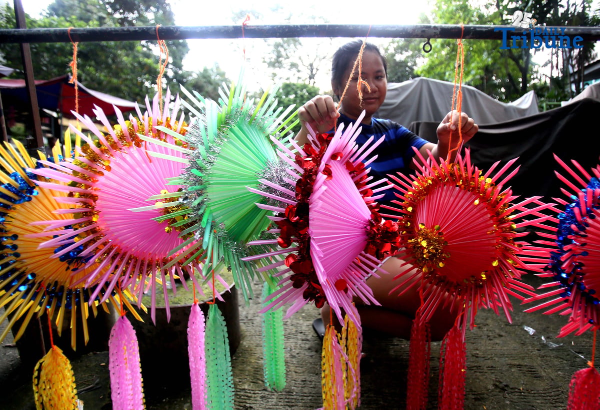 With 22 days before Christmas, a woman inspects a handmade lantern crafted from disposable straws in their compound on Wednesday, December 3. She said they created the décor to help bring the Christmas spirit to the community.