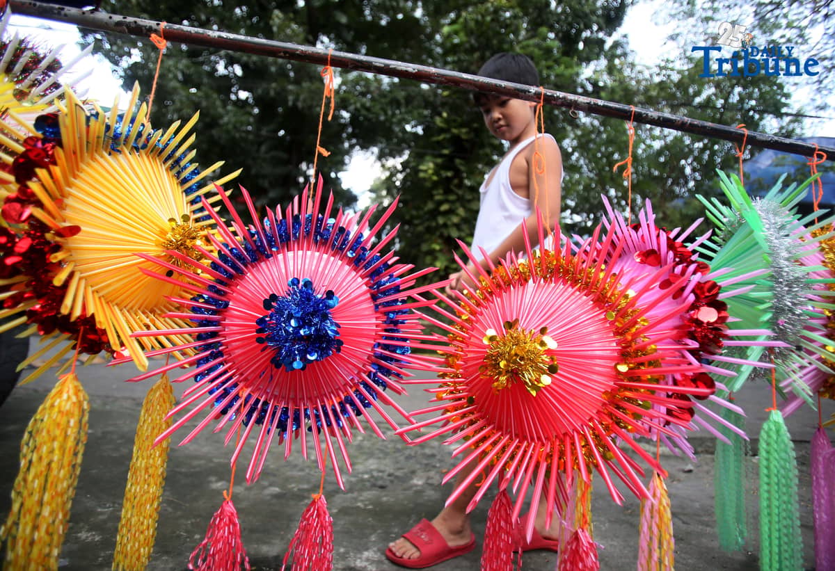 With 22 days before Christmas, a woman inspects a handmade lantern crafted from disposable straws in their compound on Wednesday, December 3. She said they created the décor to help bring the Christmas spirit to the community.