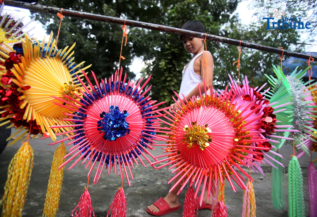 With 22 days before Christmas, a woman inspects a handmade lantern crafted from disposable straws in their compound on Wednesday, December 3. She said they created the décor to help bring the Christmas spirit to the community.