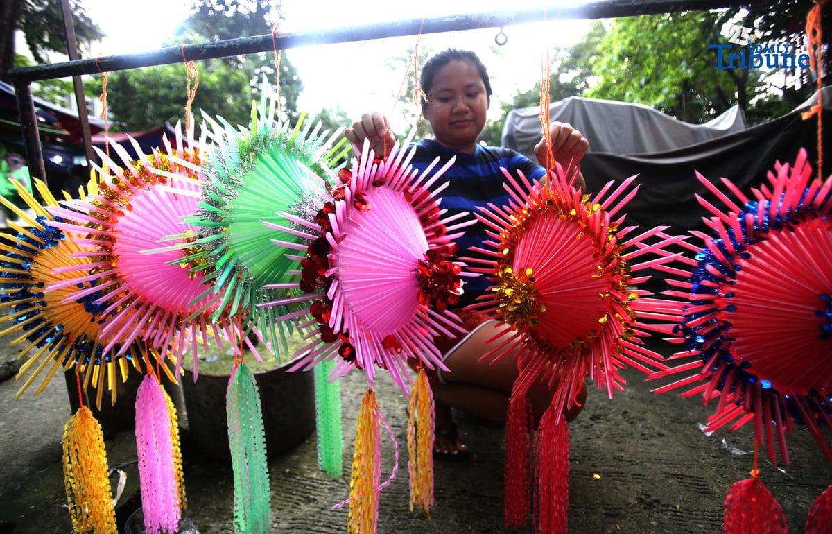 With 22 days before Christmas, a woman inspects a handmade lantern crafted from disposable straws in their compound on Wednesday, December 3. She said they created the décor to help bring the Christmas spirit to the community.