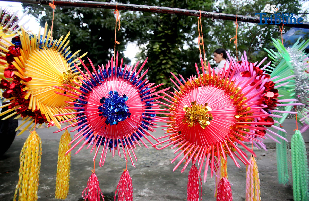 With 22 days before Christmas, a woman inspects a handmade lantern crafted from disposable straws in their compound on Wednesday, December 3. She said they created the décor to help bring the Christmas spirit to the community.