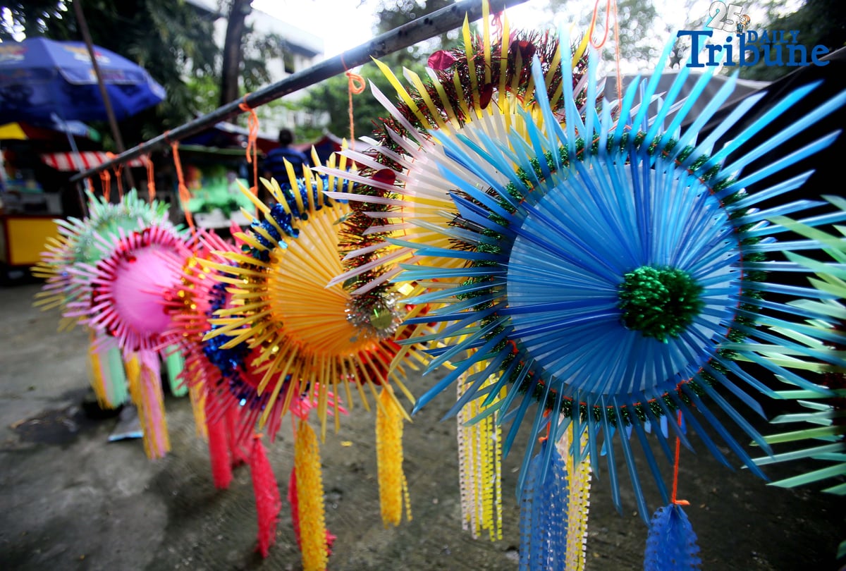 With 22 days before Christmas, a woman inspects a handmade lantern crafted from disposable straws in their compound on Wednesday, December 3. She said they created the décor to help bring the Christmas spirit to the community.