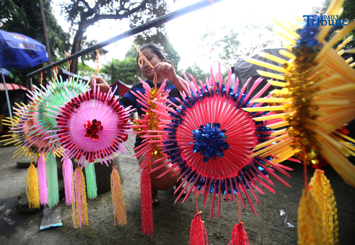 With 22 days before Christmas, a woman inspects a handmade lantern crafted from disposable straws in their compound on Wednesday, December 3. She said they created the décor to help bring the Christmas spirit to the community.