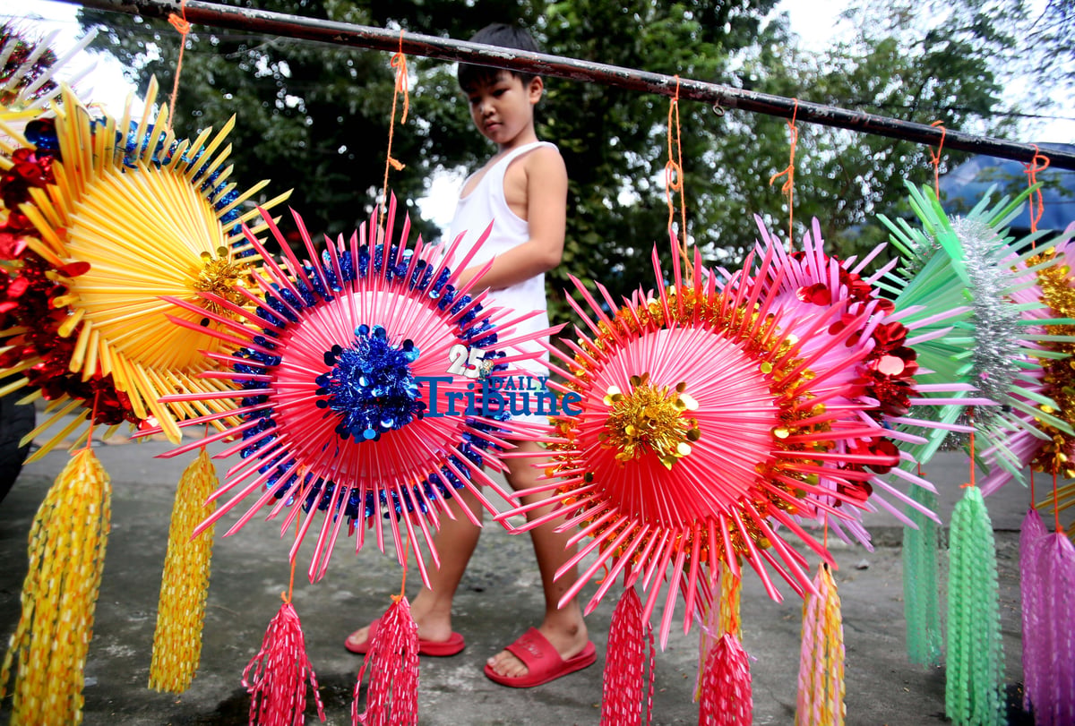 With 22 days before Christmas, a woman inspects a handmade lantern crafted from disposable straws in their compound on Wednesday, December 3. She said they created the décor to help bring the Christmas spirit to the community.