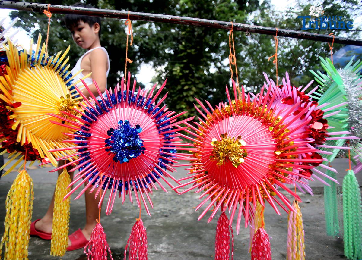 With 22 days before Christmas, a woman inspects a handmade lantern crafted from disposable straws in their compound on Wednesday, December 3. She said they created the décor to help bring the Christmas spirit to the community.