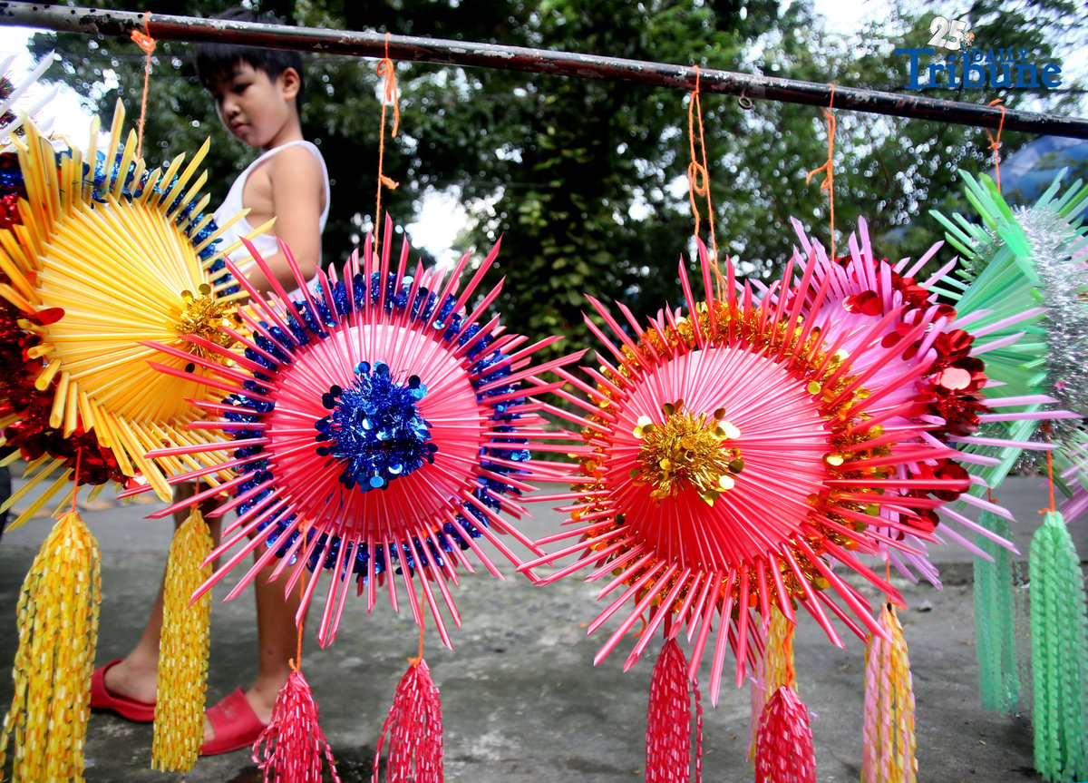 With 22 days before Christmas, a woman inspects a handmade lantern crafted from disposable straws in their compound on Wednesday, December 3. She said they created the décor to help bring the Christmas spirit to the community.