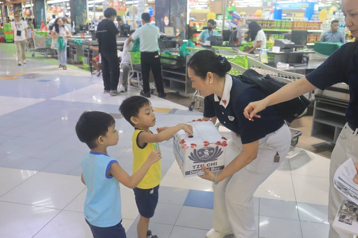 A TZU Chi volunteer receives donations from two boys at the Metro Market! Market! in Bonifacio Global City, Taguig City on 30 November 2025.