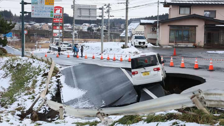 A vehicle rests on the edge of a collapsed road in Tohoku town in Aomori Prefecture following a 7.5 magnitude earthquake off northern Japan. A big quake off northern Japan left at least 30 injured, authorities said on 9 December, damaging roads and leaving thousands without power in freezing temperatures.