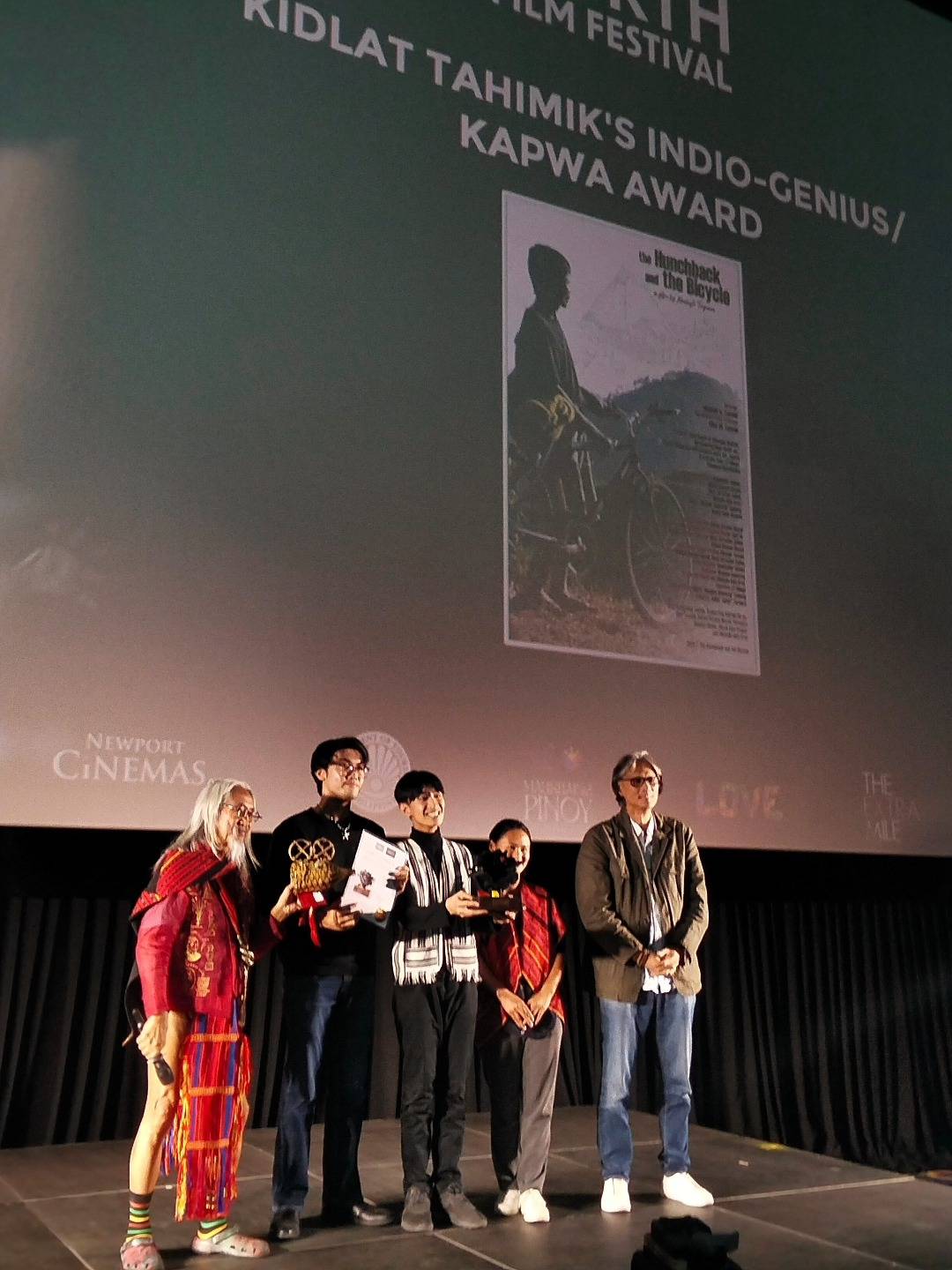 National Artist for Film, Kidlat Tahimik (far left), bestowed the Indio-Genius/Kapwa Award to the documentary "The Hunchback and The Bicycle," along with festival director Gab Malvar (far right).