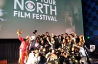 The winners of the 2025 Know Your North Film Festival take a group selfie using Kidlat Tahimik's bamboo camera.