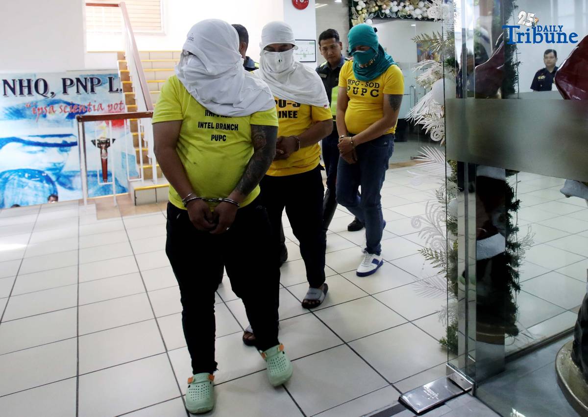 Three of the six suspects arrested in connection with the seizure of undocumented and smuggled cigarettes worth an estimated P143 million are escorted by members of the Philippine National Police–Highway Patrol Group at Camp Crame in Quezon City on Friday.