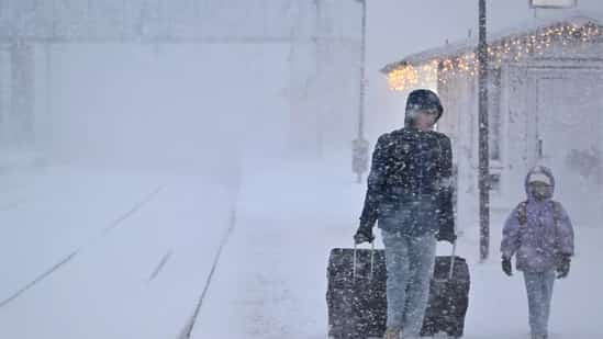 A WOMAN and child make their way with their luggage at the train station in Are as storm Johannes moves in over northern Sweden causing cancelled departures. (AFP)