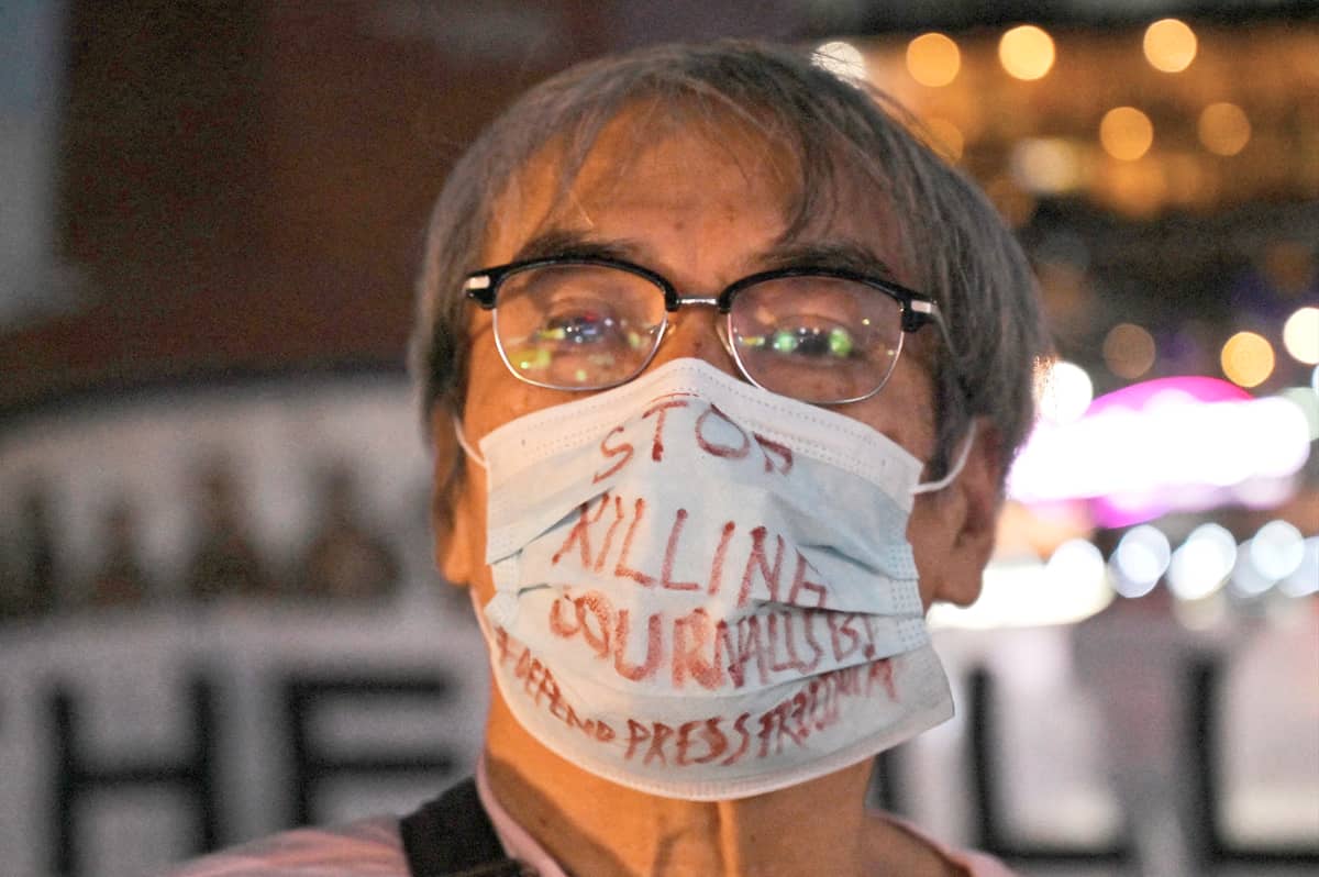 IN the Philippines wears the warning on his face: stop killing us. Between visor and mask, the message is the same — telling the truth remains a dangerous act, yet one worth protecting