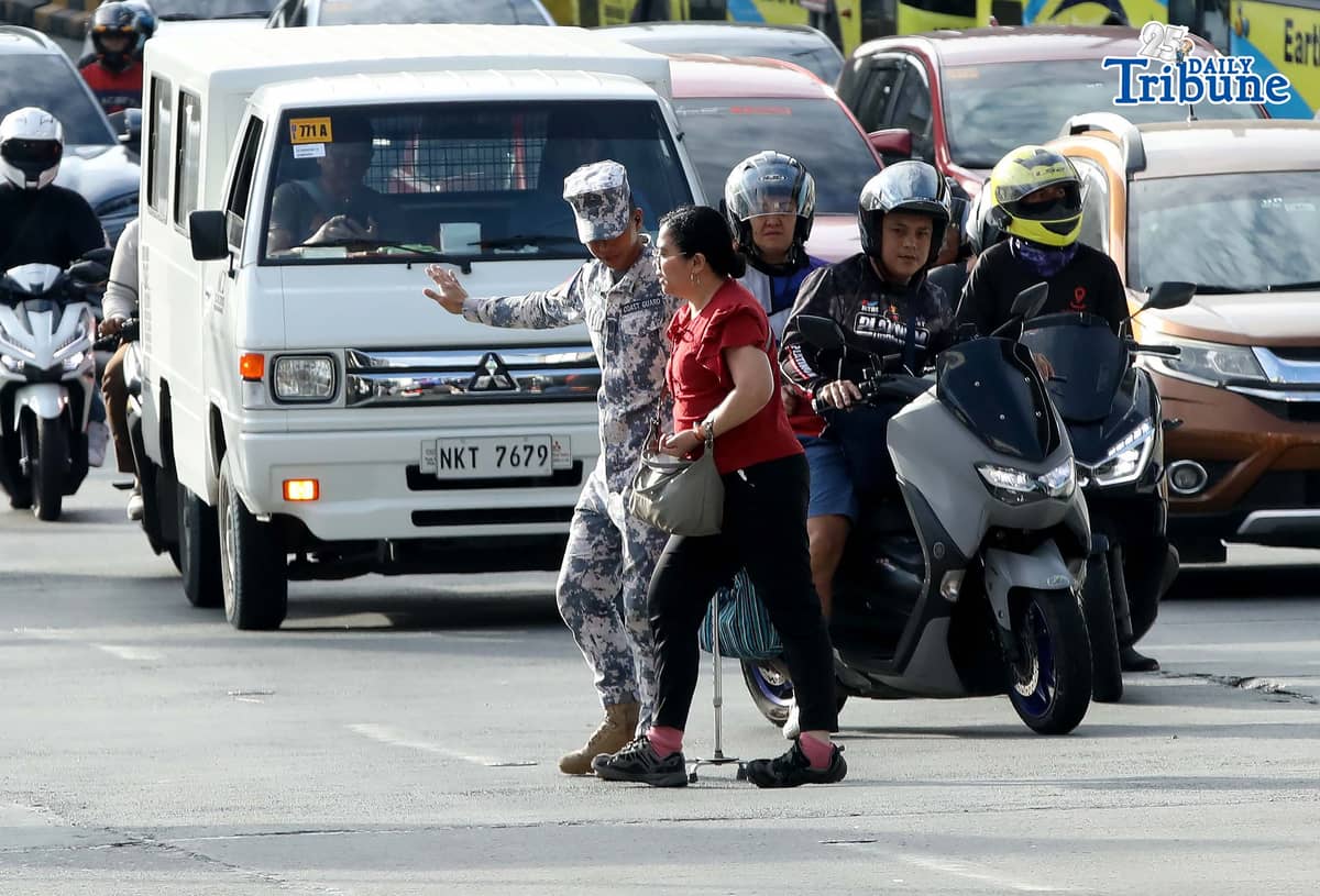 (January 05 2026) A Coast Guard personnel seen helping the PWD a passenger from a carousel bus crossing Edsa on Monday January 5 2026. Photo/Analy Labor