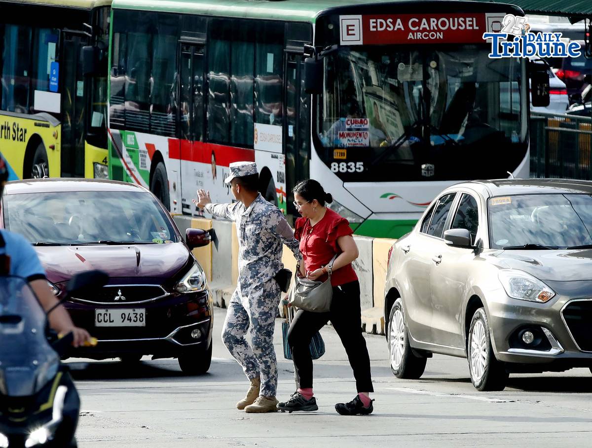 (January 05 2026) A Coast Guard personnel seen helping the PWD a passenger from a carousel bus crossing Edsa on Monday January 5 2026. Photo/Analy Labor