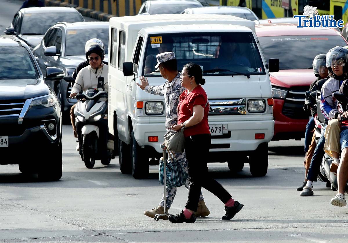 (January 05 2026) A Coast Guard personnel seen helping the PWD a passenger from a carousel bus crossing Edsa on Monday January 5 2026. Photo/Analy Labor