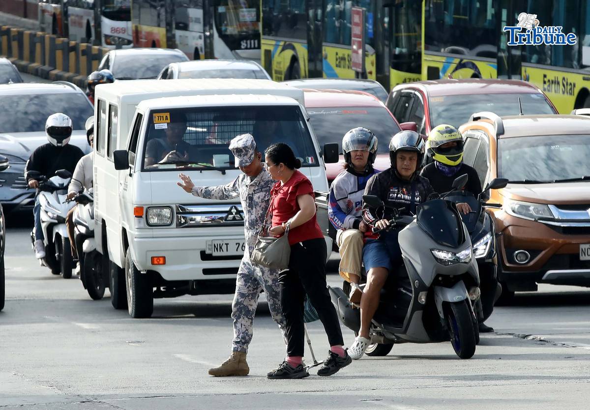 (January 05 2026) A Coast Guard personnel seen helping the PWD a passenger from a carousel bus crossing Edsa on Monday January 5 2026. Photo/Analy Labor