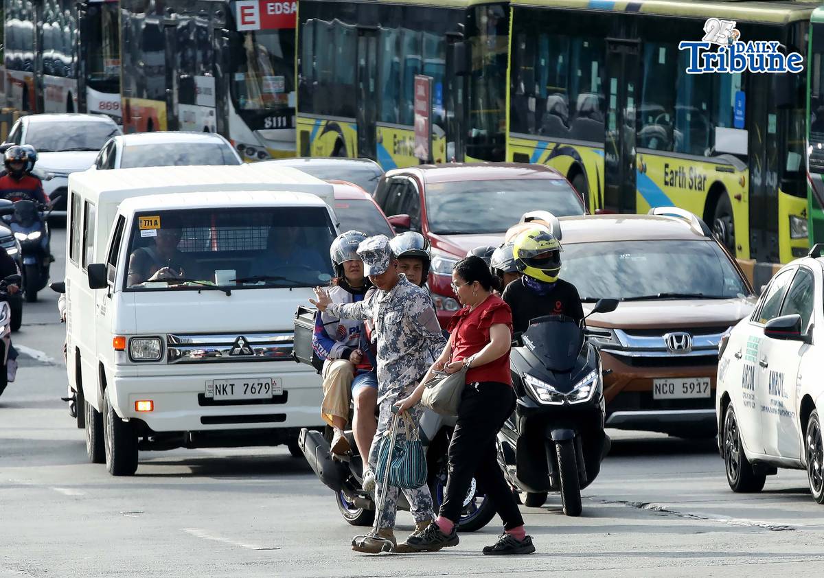 (January 05 2026) A Coast Guard personnel seen helping the PWD a passenger from a carousel bus crossing Edsa on Monday January 5 2026. Photo/Analy Labor
