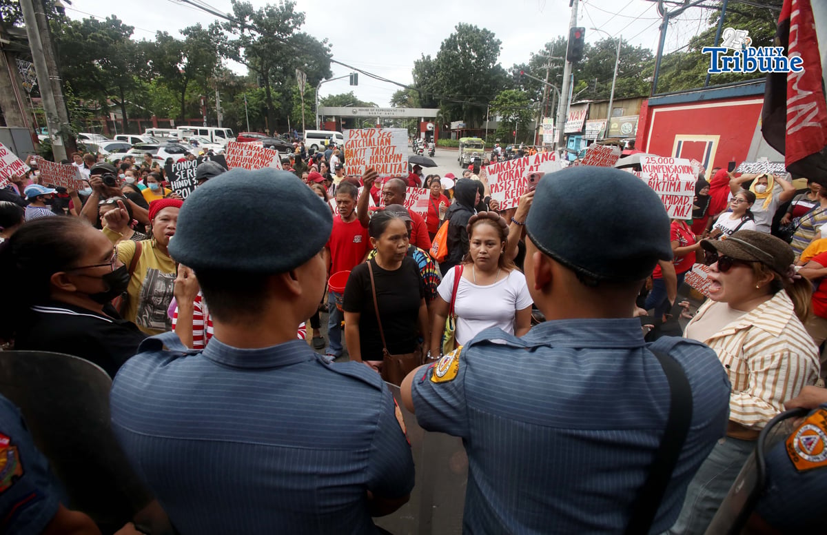 Militant groups stage a protest outside the DSWD Central Office in Batasan, Quezon City on Monday, demanding the immediate release of ₱25,000 in compensation for each family affected by recent disasters.