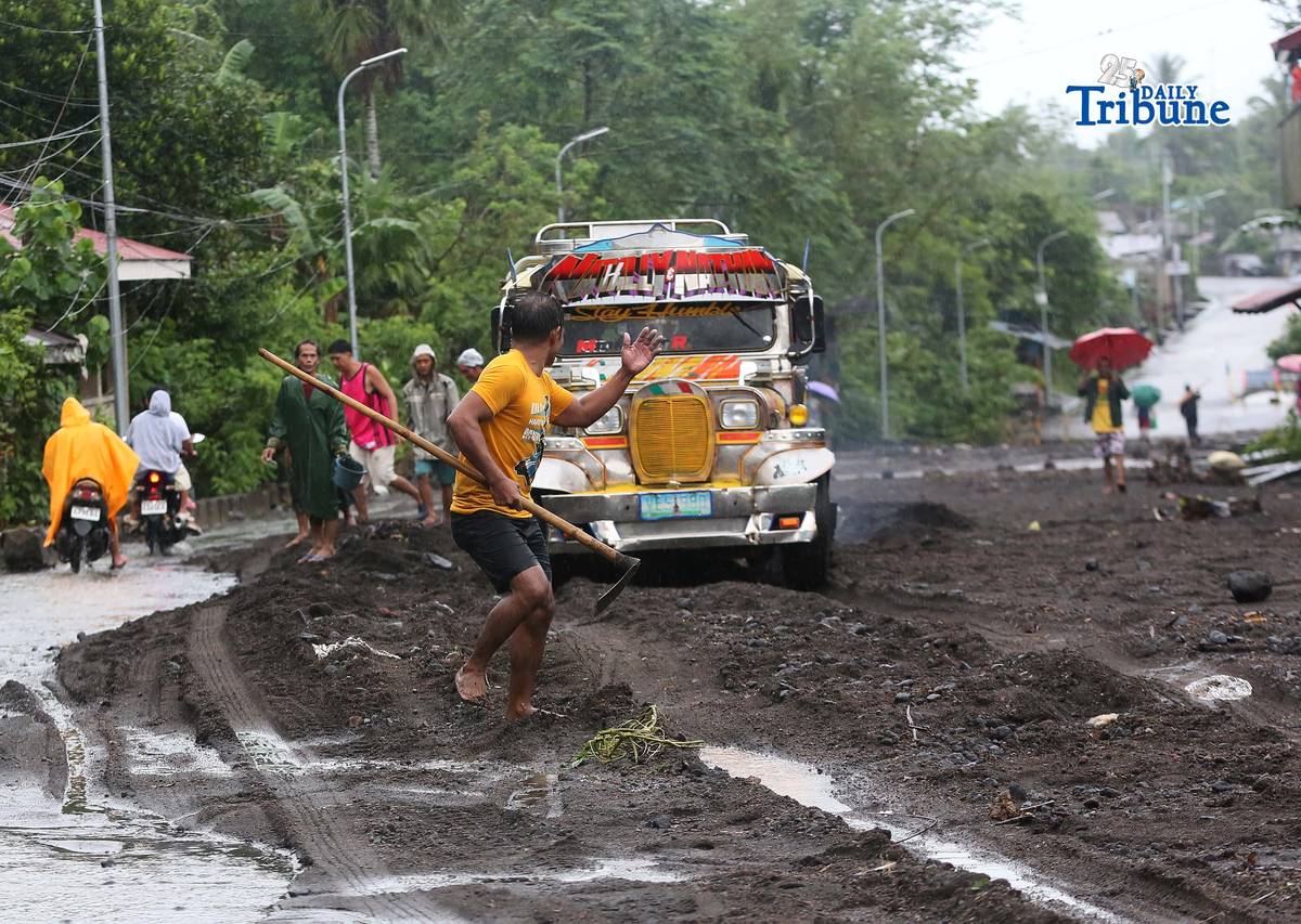 (January 17 2026) To help motorists passing through at the road in Brgy Masarawag, Guinobatan Albay, on Saturday January 17 2026, residents removed the sand and rocks scattered along the road because of flooding due to Tropical storm Ada on Saturday January 17 2026. Photo/Analy Labor