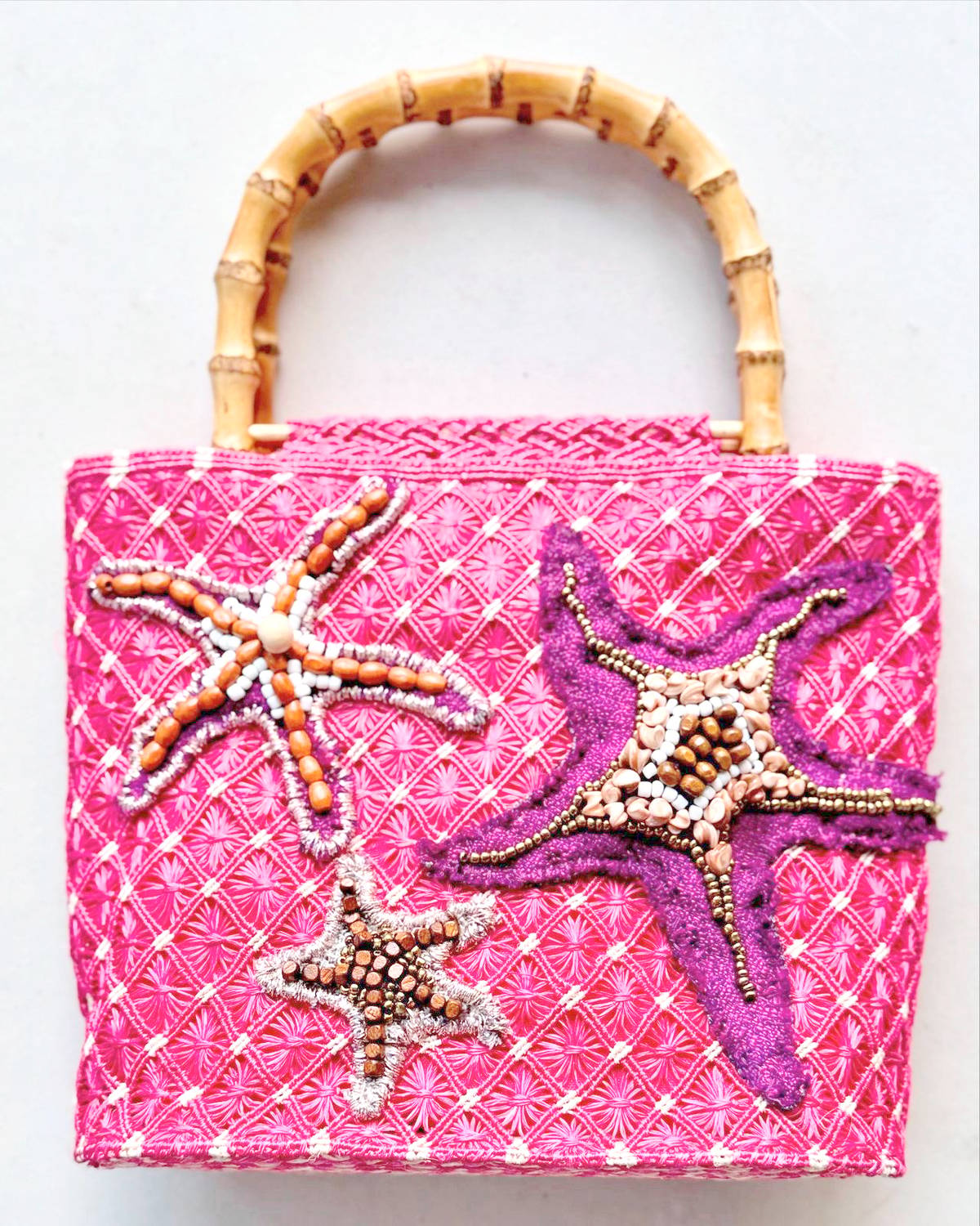 KARIMA abaca bag by AudreyAlbason is from the collection called ‘tala’ which is the Filipino word for “star”. The starfish reimagined into various shapes and interpreted in combinations of shells, wooden beads, tweed, and tartan in vibrant colors on intricate macrame squares.  This is rendered in vibrant pink and embellished with starfishes with dimensions 7’X 10.10’ with bamboo handle.