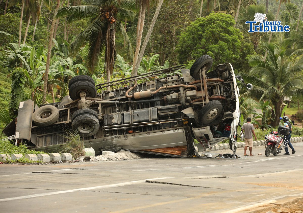 A six-wheeler truck loaded with coconut lumber overturned along the Gumaca bypass road in Quezon on Tuesday. Bystanders said the vehicle lost balance due to the wet and slippery road conditions.