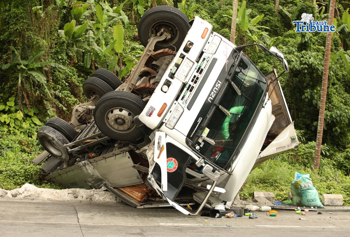 A six-wheeler truck loaded with coconut lumber overturned along the Gumaca bypass road in Quezon on Tuesday. Bystanders said the vehicle lost balance due to the wet and slippery road conditions.