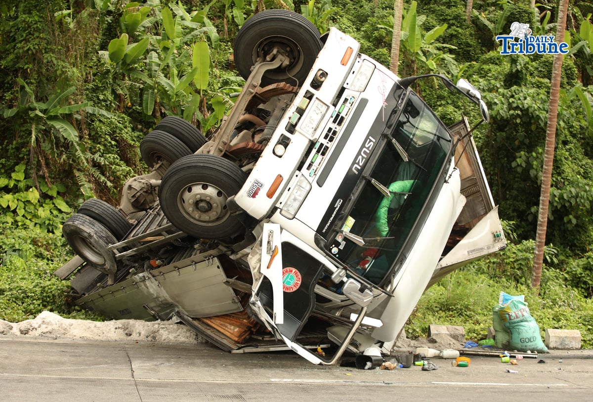 A six-wheeler truck loaded with coconut lumber overturned along the Gumaca bypass road in Quezon on Tuesday. Bystanders said the vehicle lost balance due to the wet and slippery road conditions.