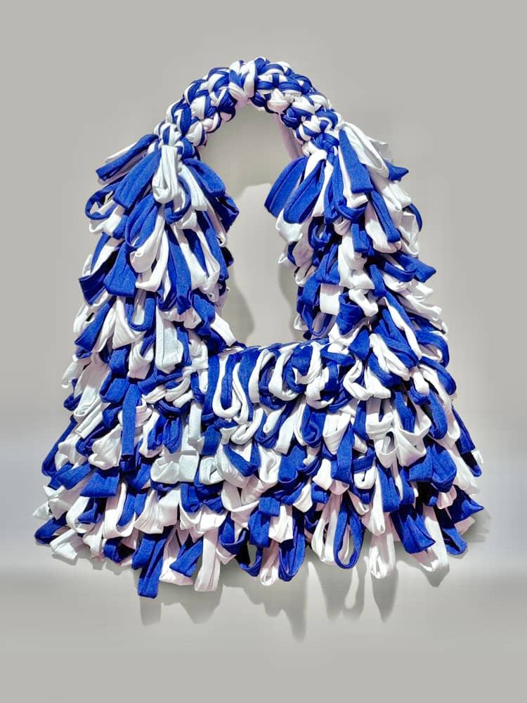 BLUE White Wisteria bindle bag is designed by Ria Bolivar for her personal brand ‘Reveri’, crocheted carefully by her using T-shirt yarn. The bag is spacious and its handle is very pleasant to hold, reflecting its creative concept of freedom and comfort. Dimensions: 14” x 7.5” x 5”