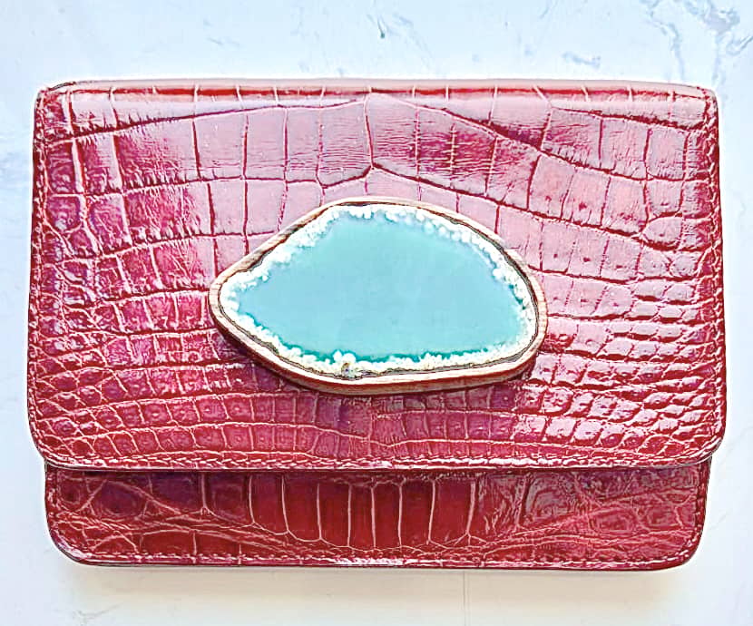 AMELIE Bag by Celestina Manila is the wonders and beauty found underneath the earth and its waters celebrating  its uniqueness because no two will ever be alike. Each shaped by nature, each marked by time — never repeated, never the same. made from siamensis(belly side), hand clutch in burgundy wine is highlighted by a green agate wrapped in kamagong wood