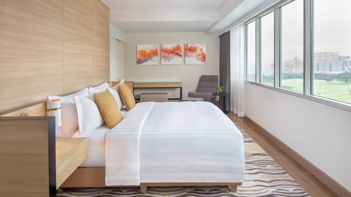 THE Suite Room features a contemporary, elegant interior centered on a generously sized bed.
