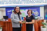 CDC President and CEO Atty. Agnes VST Devanadera receives the award from DOT Region 3 Director Richard Daenos, who cited the CDC’s role in elevating service standards in Clark Freeport.