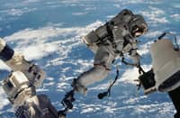 TETHERED to the void Anchored by a foot restraint on the ISS Canadarm2, astronaut David A. Wolf drifts above Earth, turning silence and vacuum into a workplace during the first extravehicular activity of the STS-112 mission.