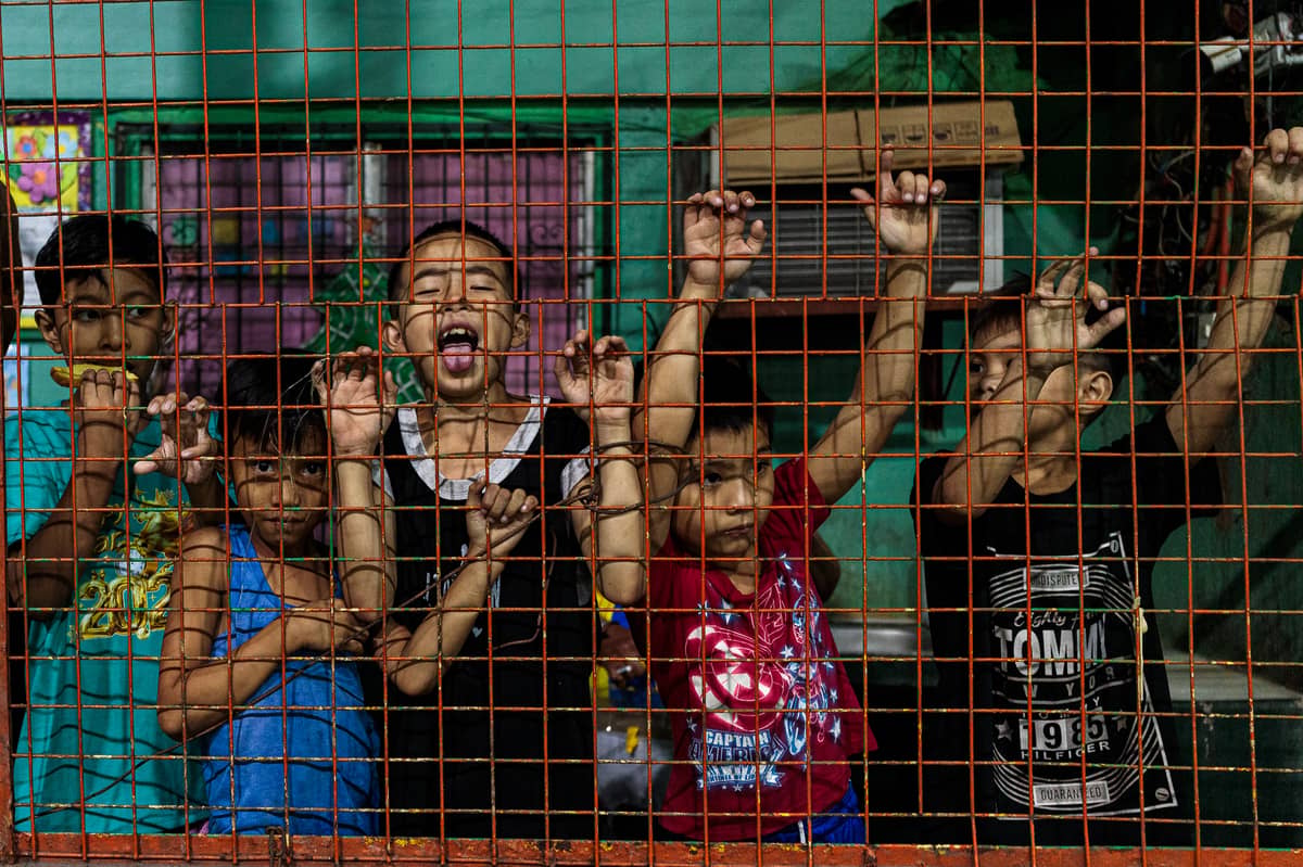 Children watch through the basketball court fence as Philippine Rui Dragon Dance group practices in downtown Manila on Friday, 6 February 2026.
