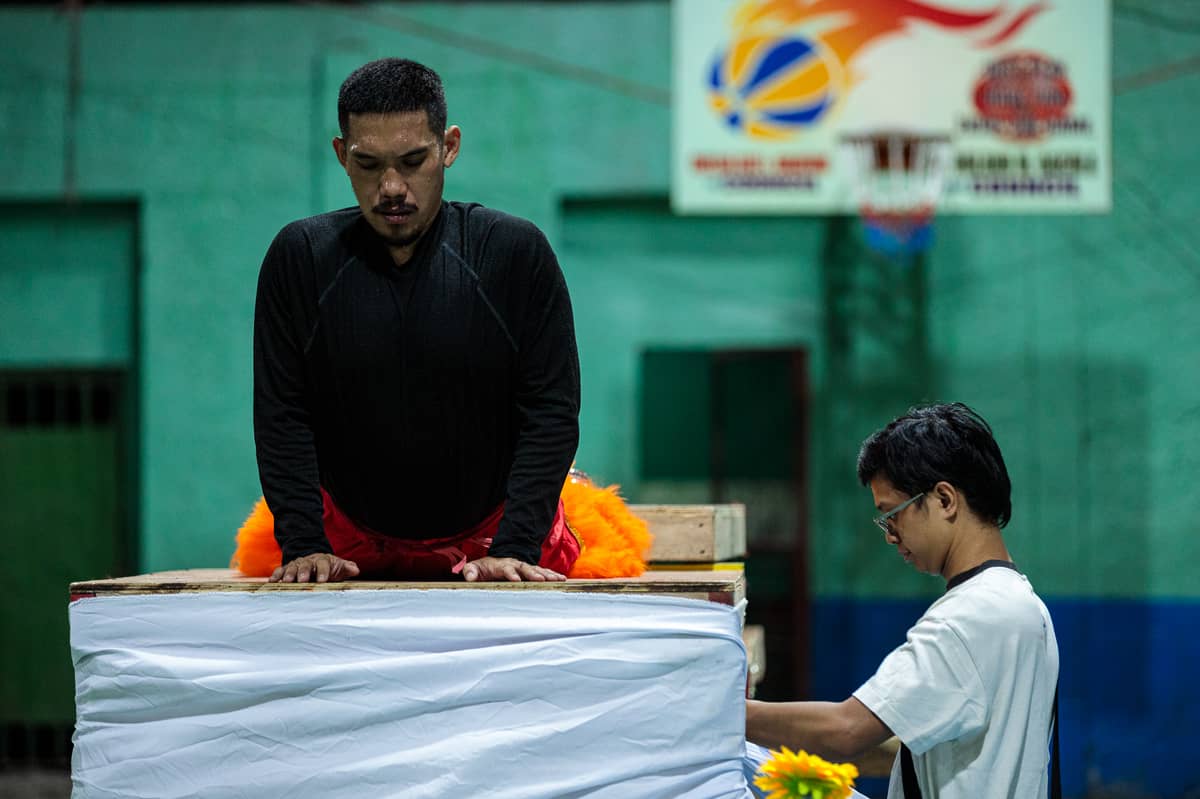 King Noah stretches atop a wooden platform during a practice for an upcoming lion dance competition. As demand for lion and dragon dance performances peaks only during the Chinese New Year, members of the Philippine Rui Dragon Dance group maintain their own day jobs to make ends meet.