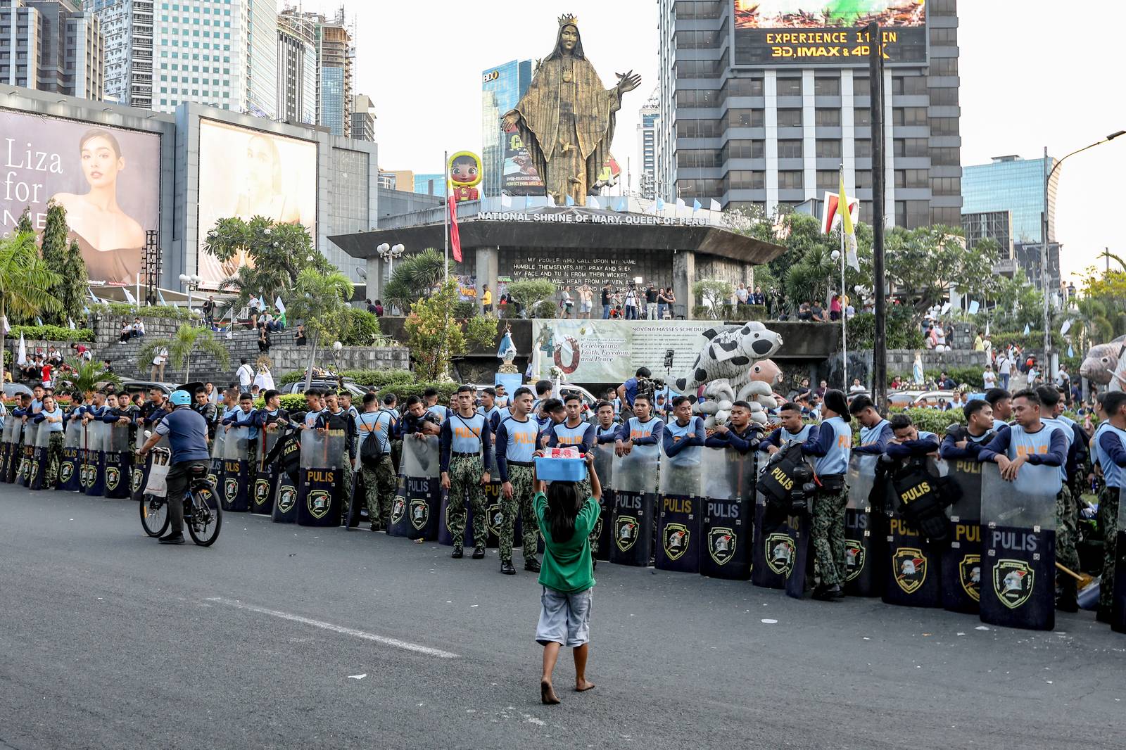 An under age vendor crosses Ortigas Avenue where a police barricade is seen in front of EDSA Shrine.