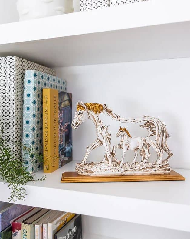 SHELF vignette layering glass and ceramic equine figurines.