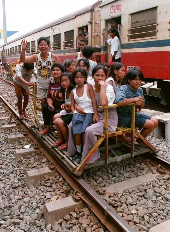 RESIDENTS take short trips aboard improvised wooden trolleys running along the Philippine National Railways tracks. The contraption is easily lifted off the rails to clear the way for a train (in the background) until the tracks are dismantled to make way for the NSCR.
