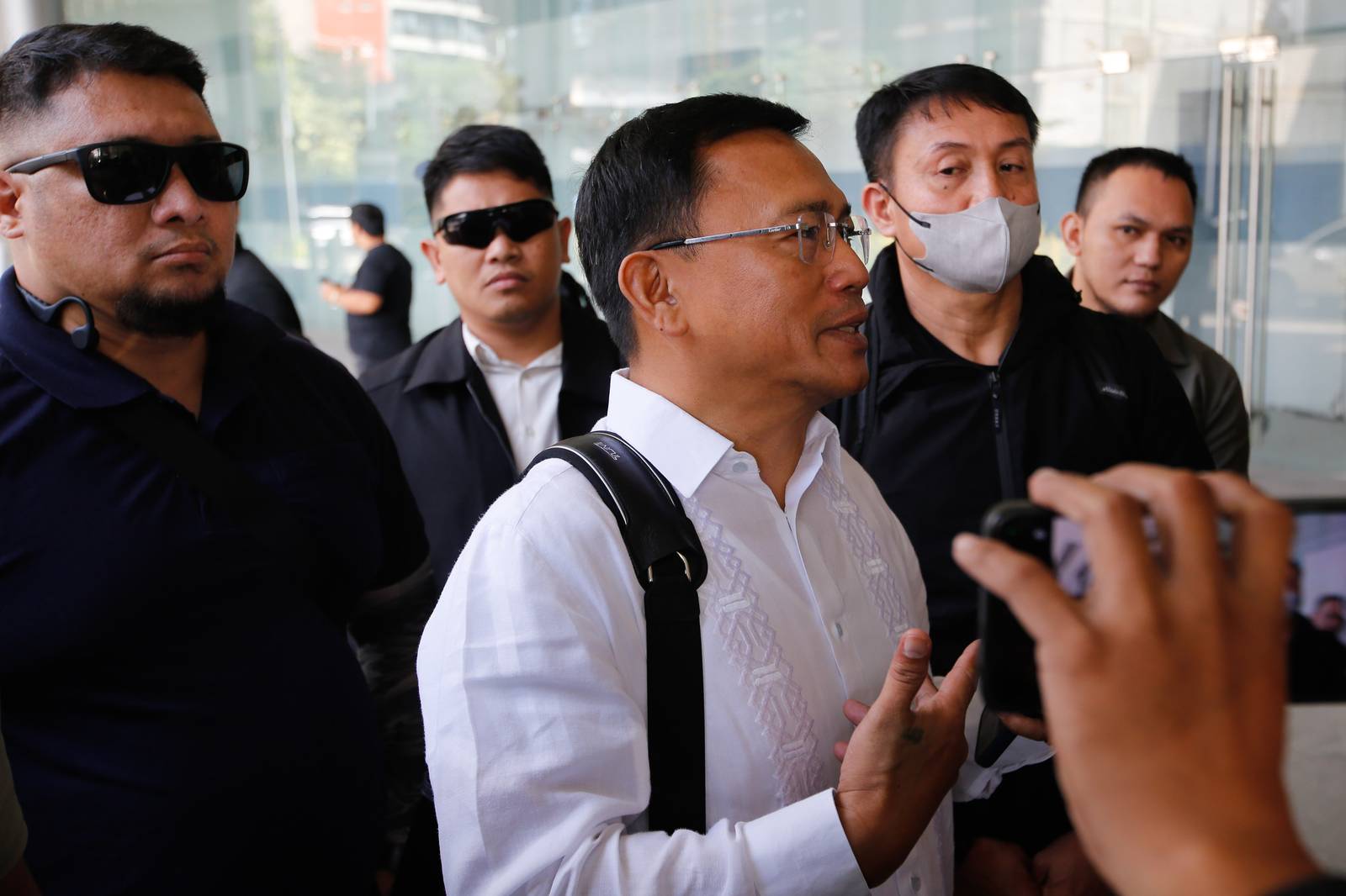 SUBPOENA SHOWDOWN. Lawyer Levito Baligod, accompanied by several alleged former Marines, arrives at the National Bureau of Investigation headquarters in Pasay City on Thursday, 12 March 2026, after being subpoenaed over allegations that they delivered suitcases of cash to Ferdinand Marcos Jr., former House Speaker Martin Romualdez and other lawmakers.