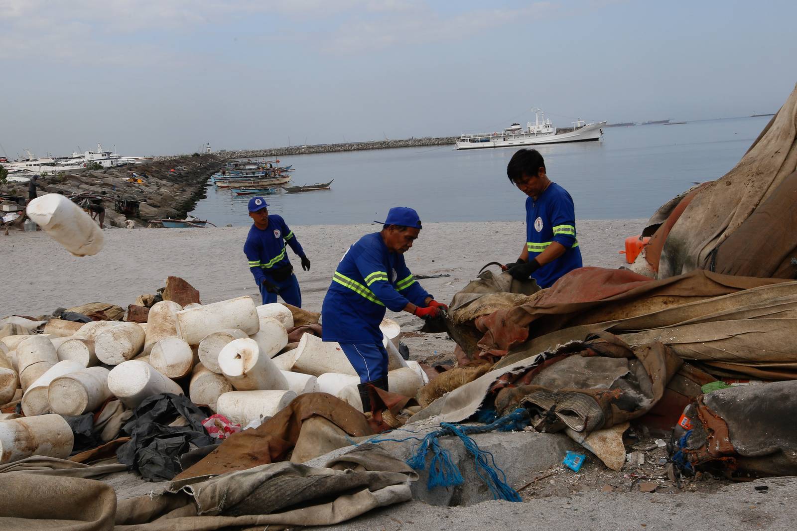 Department of Environment and Public Services personnel remove broken floating barriers in Manila Bay on Saturday, 14 March 2026. The barriers, which had long been piled at the edge of Dolomite Beach, were originally used to mark the area and prevent debris from drifting further into the water.
