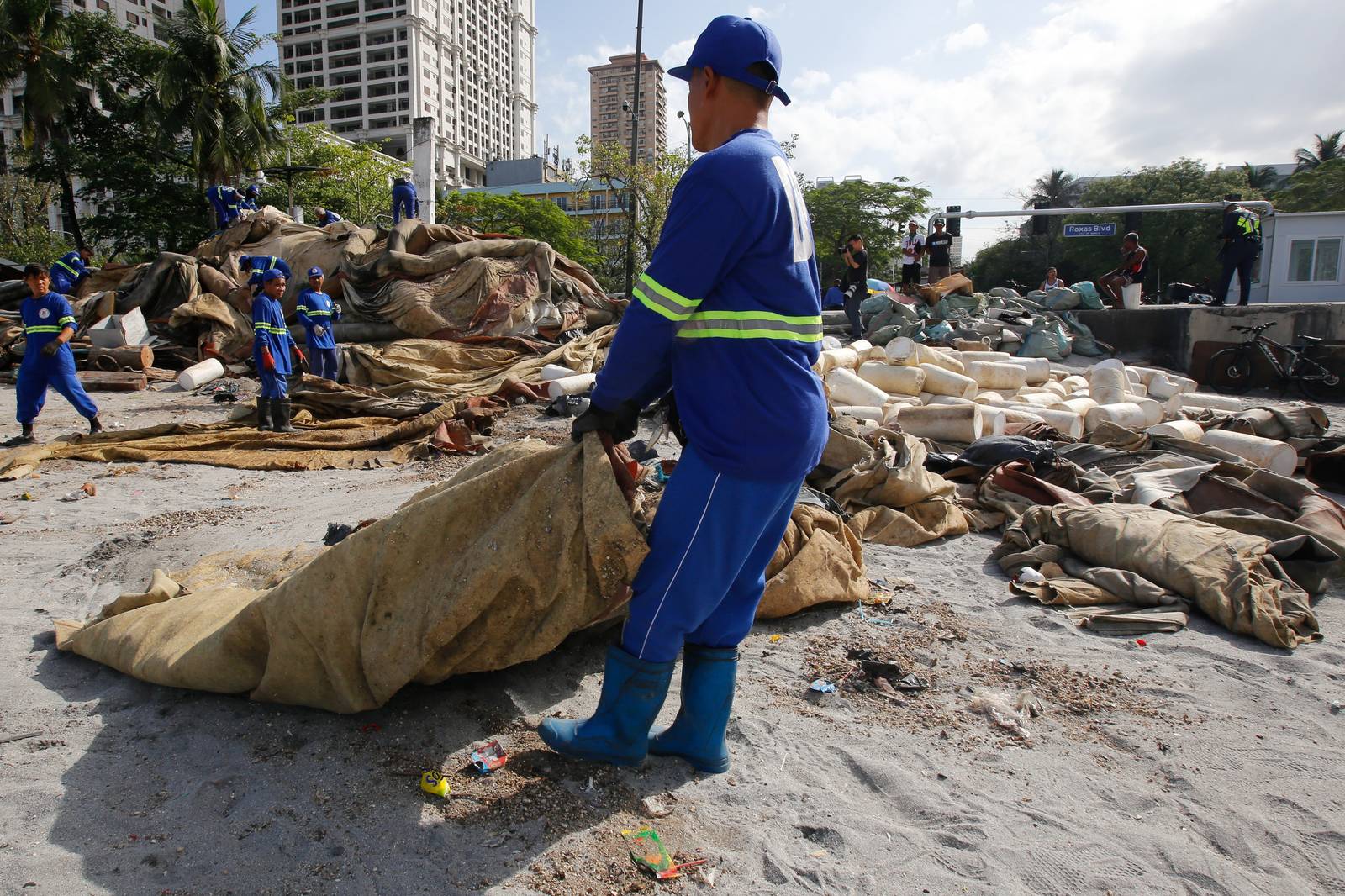 Department of Environment and Public Services personnel remove broken floating barriers in Manila Bay on Saturday, 14 March 2026. The barriers, which had long been piled at the edge of Dolomite Beach, were originally used to mark the area and prevent debris from drifting further into the water.