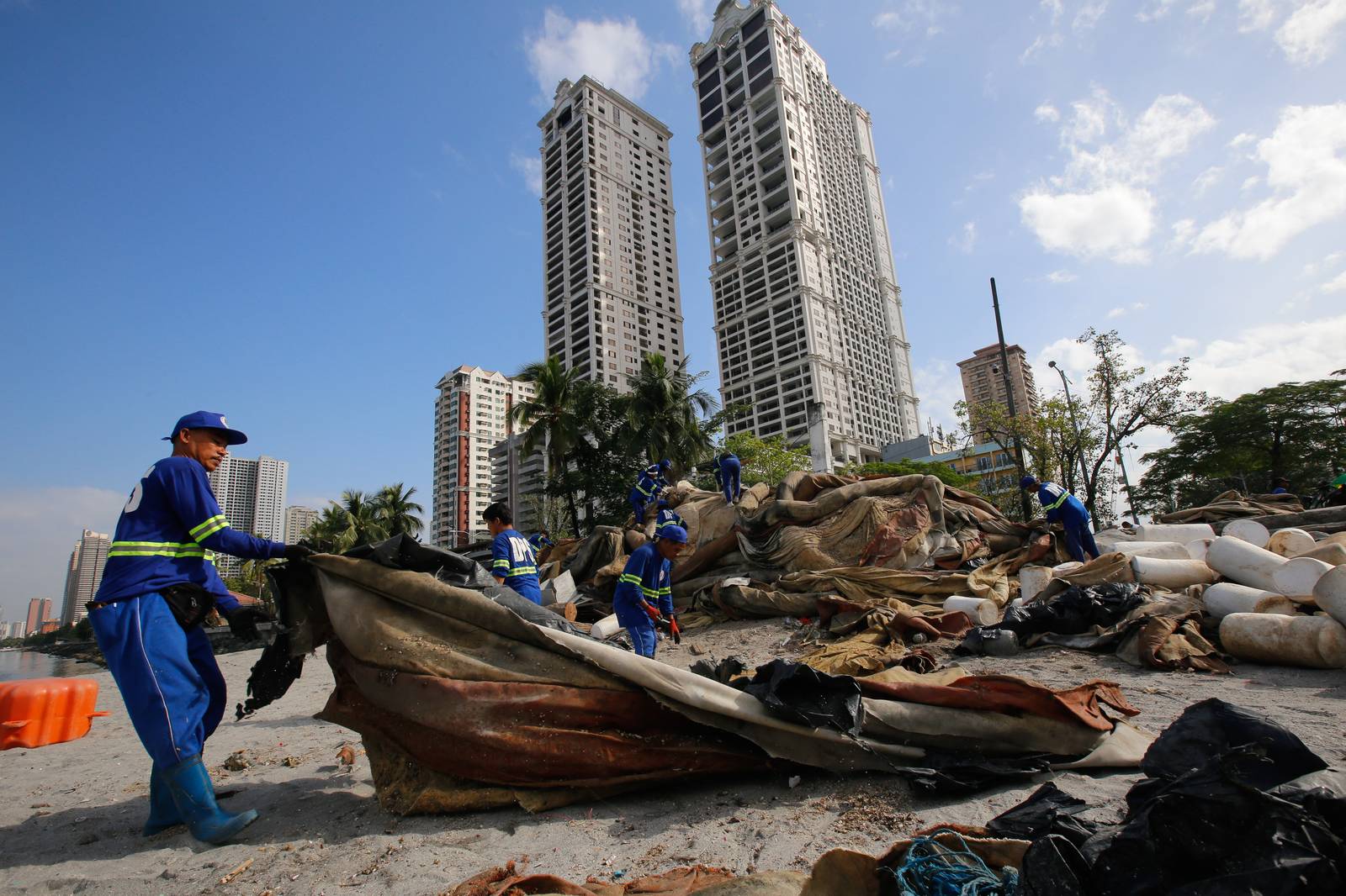 Department of Environment and Public Services personnel remove broken floating barriers in Manila Bay on Saturday, 14 March 2026. The barriers, which had long been piled at the edge of Dolomite Beach, were originally used to mark the area and prevent debris from drifting further into the water.