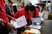 Tricycle drivers help each other as they fill out forms for the Department of Social Welfare and Development's cash aid program, in Paco, Manila on Monday, 16 March 2026.
DSWD will begin the rollout of P5,000 financial assistance to tricycle drivers in 39 designated payout centers in Metro Manila as a response to surging oil prices.