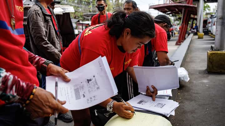 Tricycle drivers help each other as they fill out forms for the Department of Social Welfare and Development's cash aid program, in Paco, Manila on Monday, 16 March 2026.
DSWD will begin the rollout of P5,000 financial assistance to tricycle drivers in 39 designated payout centers in Metro Manila as a response to surging oil prices.