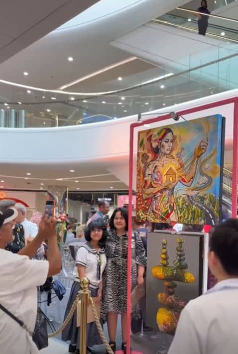 EXHIBIT-GOERS pose for photos beside artworks featured in the Sining Filipina 2026 exhibit at The Podium.